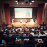 Disfocus of the speaker giving a talk on corporate Business Conference. Audience at the conference hall. Business and Entrepreneurship event